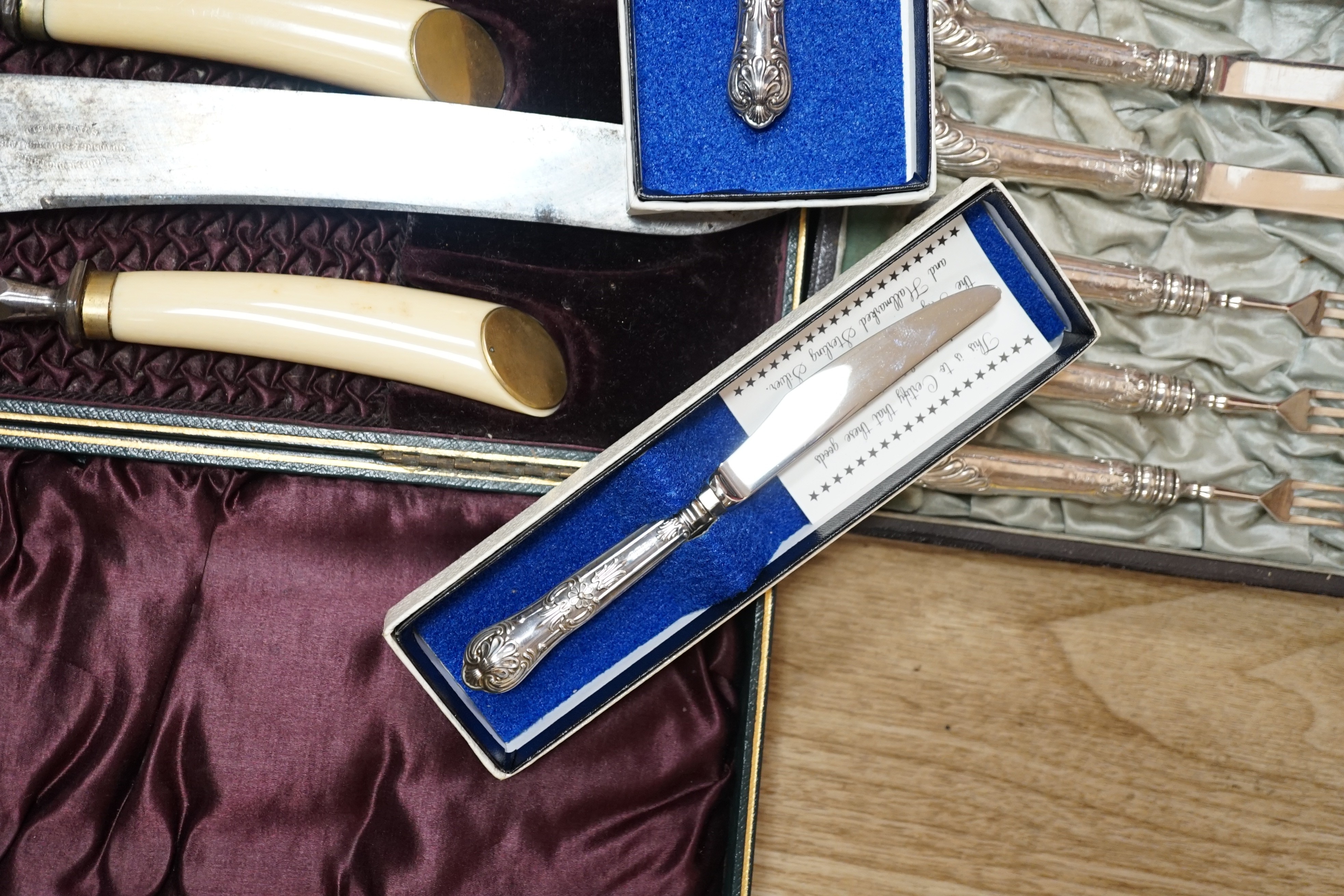 Two cased plated carving sets, a cased set of silver handled cake knives, a modern silver handled magnifying glass and cake slice.